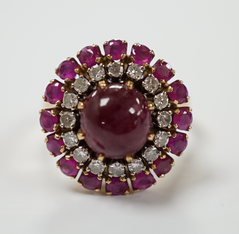 A yellow metal, ruby and diamond set circular cluster dress ring, with central cabochon ruby, size M/N, gross 8.2 grams.